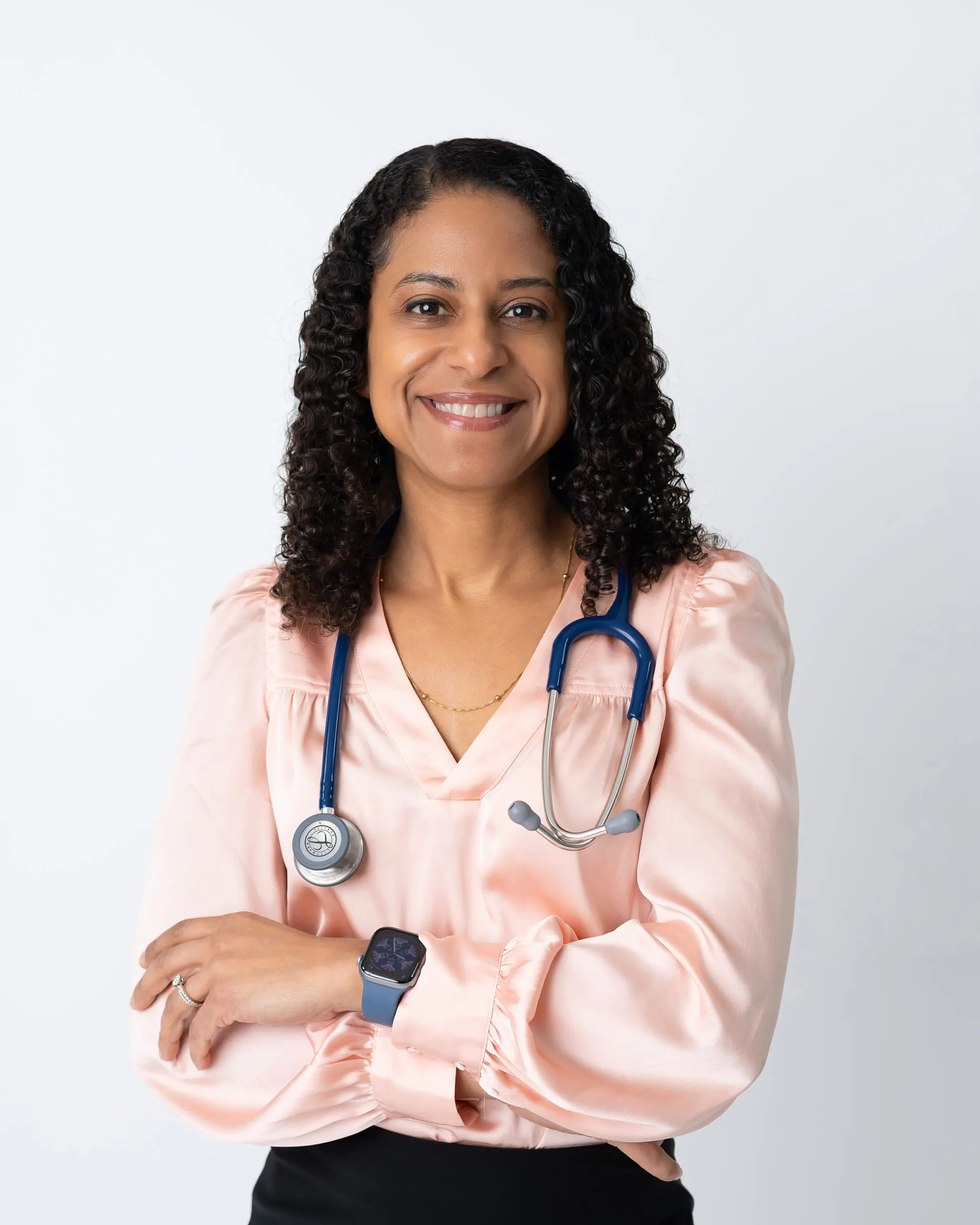 Confident female doctor with stethoscope and folded arms, smiling.