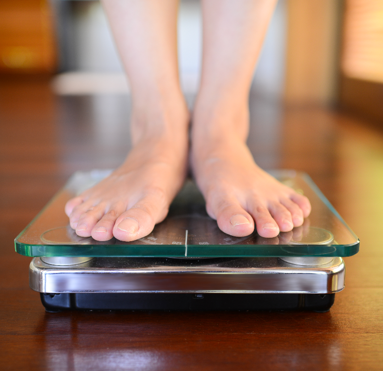 Person standing on a digital scale measuring weight.