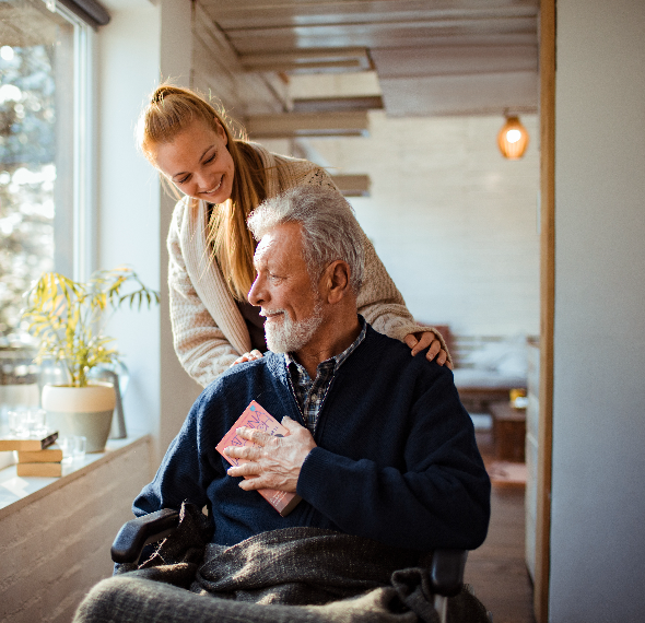 A young woman giving a gift to an elderly man in a cozy home.